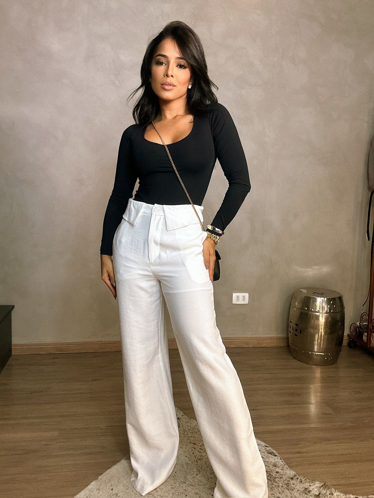 Mulher usando Body Serena manga longa preto combinado com calça branca de alfaiataria em look elegante.