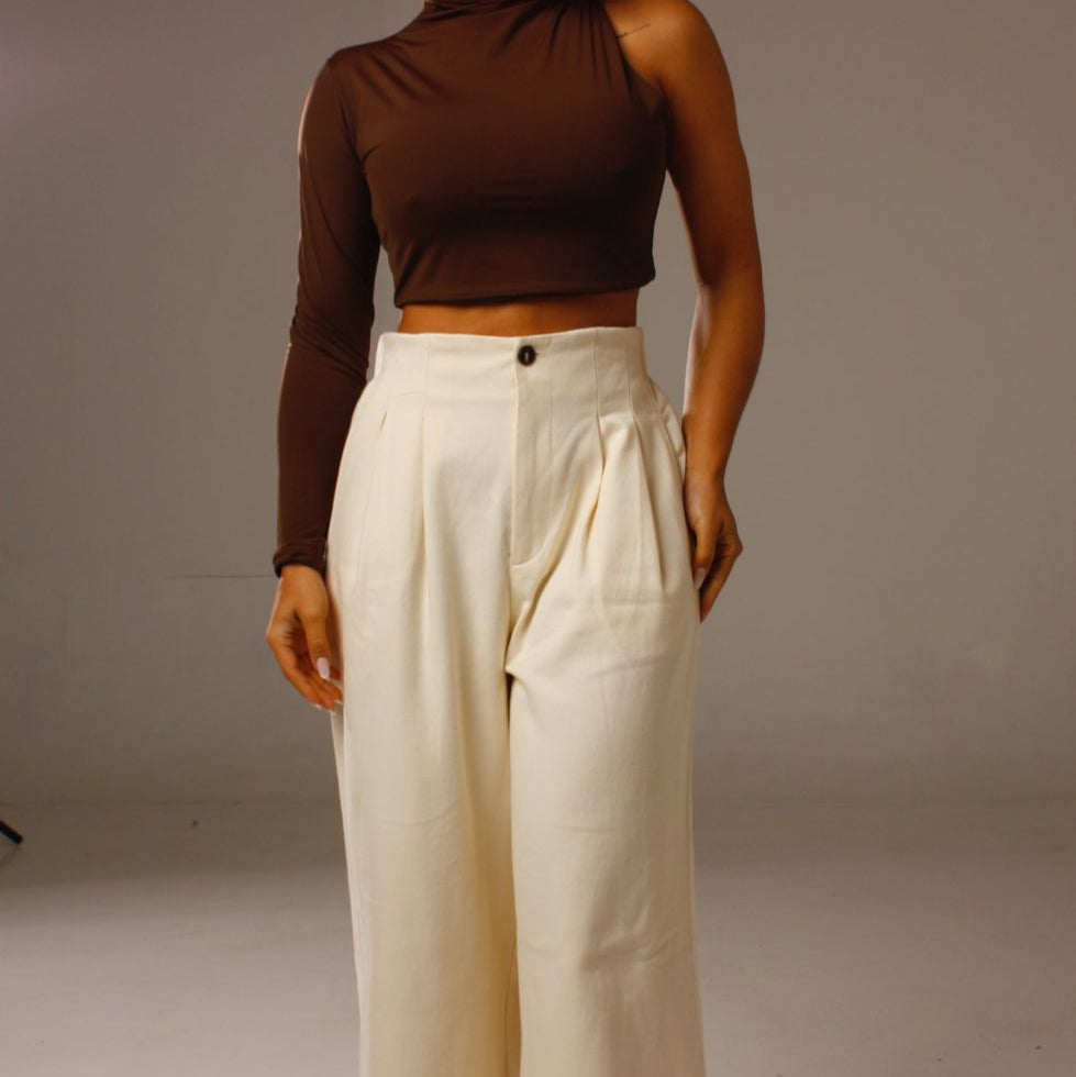Look completo com Cropped Luna 1 Ombro Só marrom e calça clara de cintura alta.