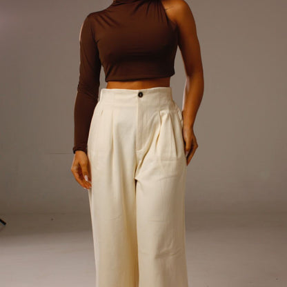Look completo com Cropped Luna 1 Ombro Só marrom e calça clara de cintura alta.